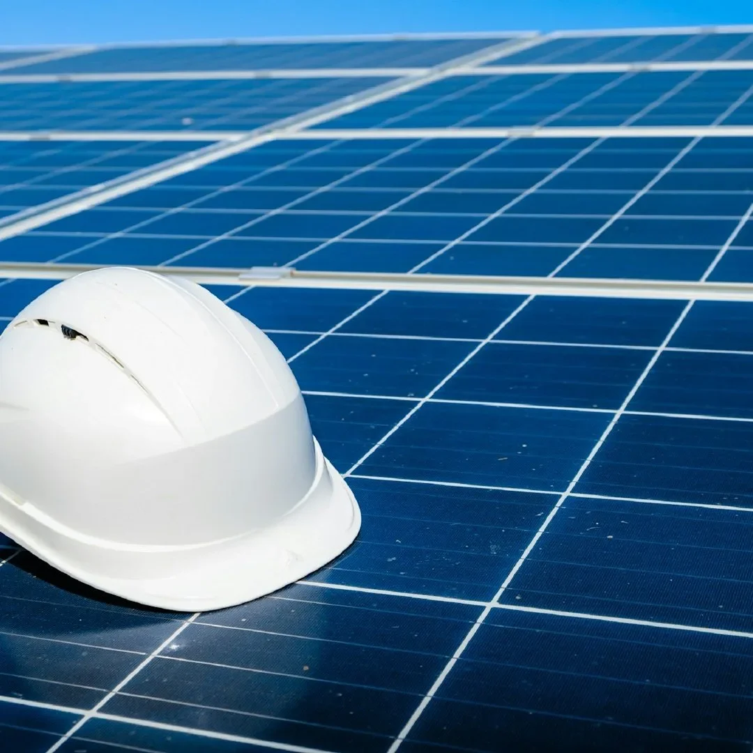White safety helmet resting on rooftop solar panels, symbolising professional solar PV installation work